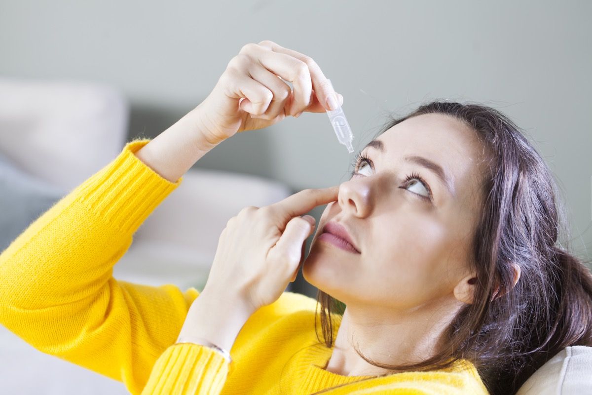 امرأة شابة تستخدم قطرات العين لعلاج العين. احمرار وجفاف العيون والحساسية وحكة في العين