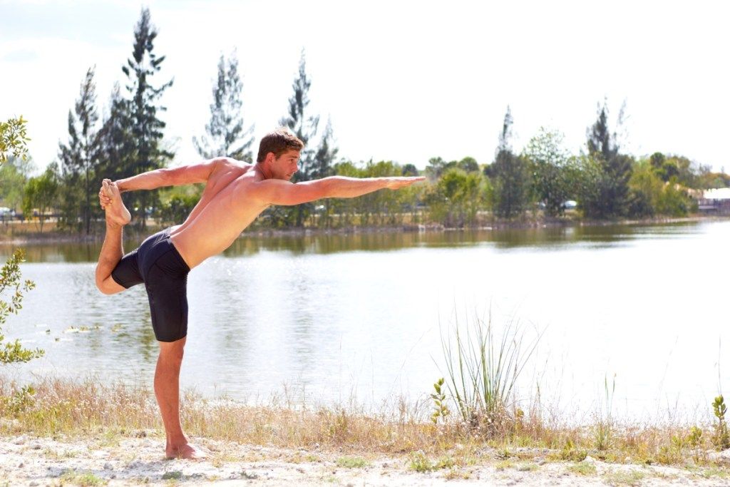 Човек, занимаващ се с йога и балансиращ на един крак здрав мъж