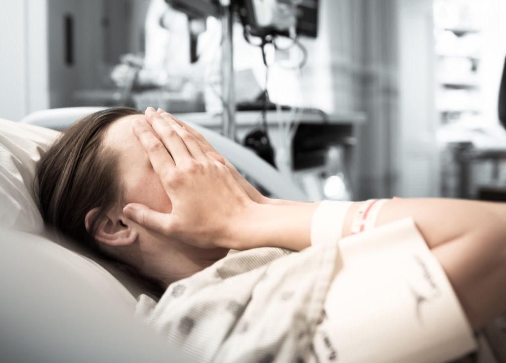 Mulher chorando em uma cama de hospital.