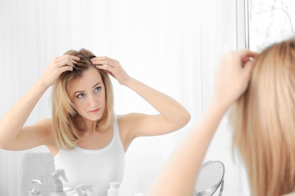 donna che guarda le radici dei suoi capelli, i modi in cui il tuo corpo cambia dopo i 40 anni