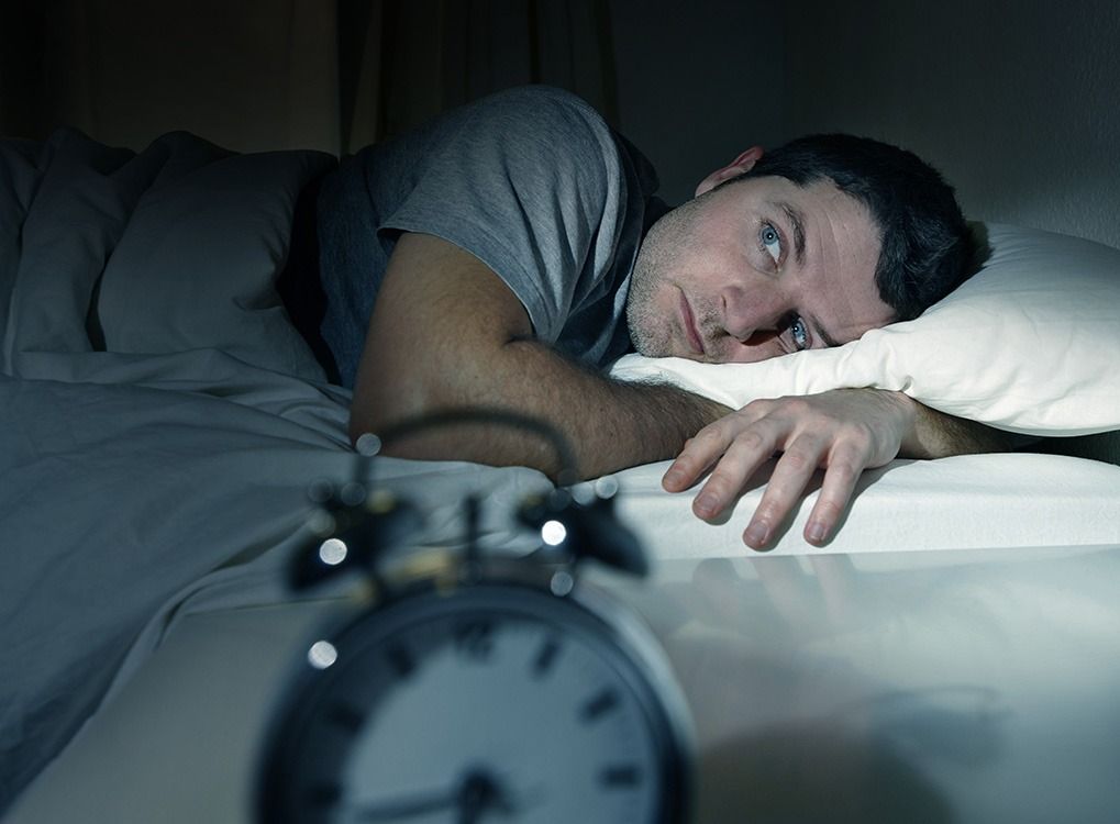 알람 시계를보고있는 침대에있는 남자, 40 세 이후에 몸이 변하는 방식