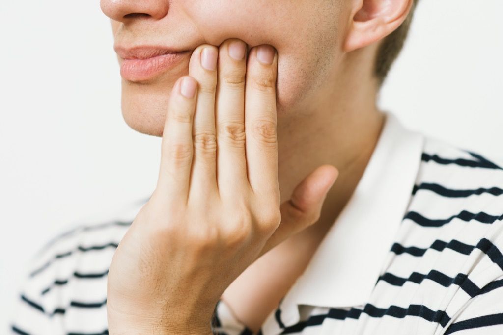 Person, die Zahnschmerzen hat, die ihren Kiefer halten, wie sich Ihr Körper nach 40 verändert