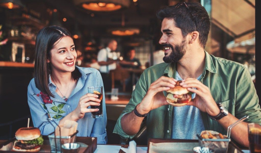 Par som äter hamburgare på en restaurang för middag