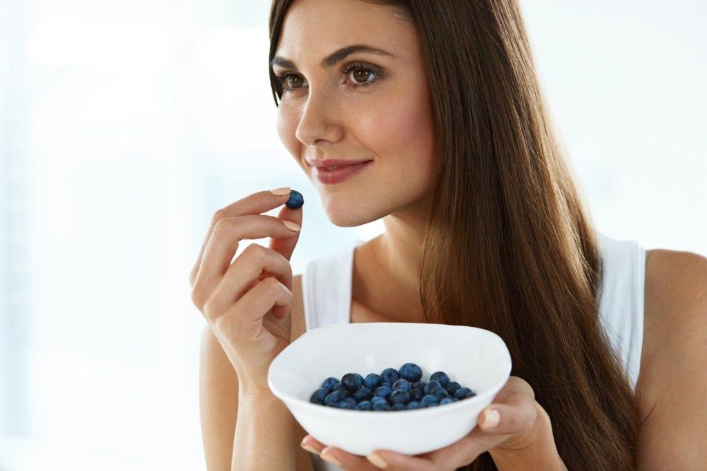 Wanita mengunyah sebilangan blueberry
