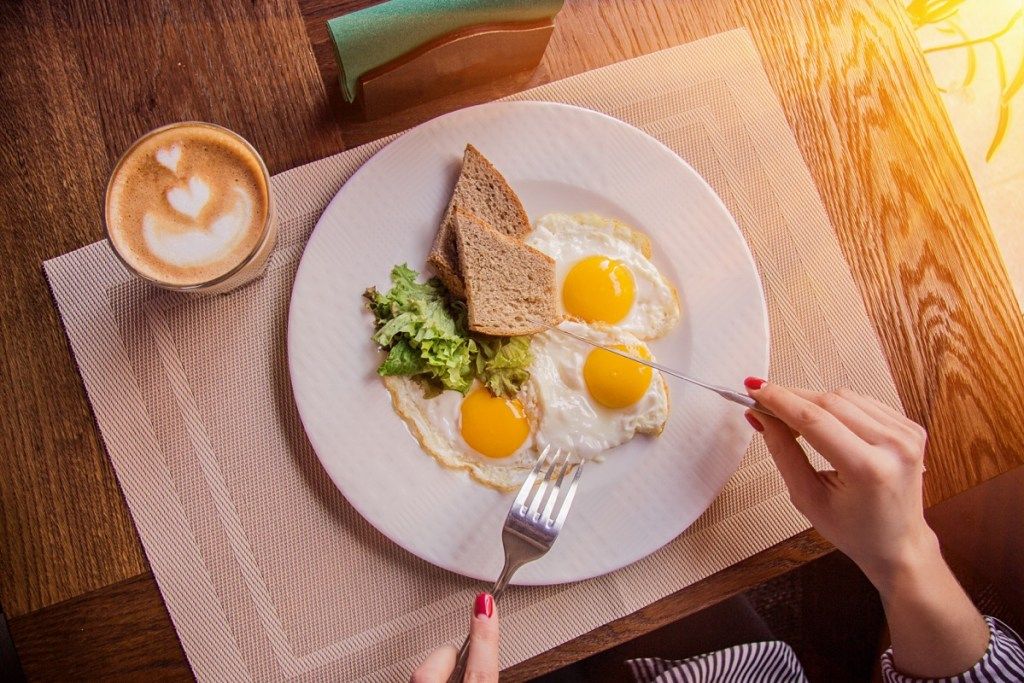 朝食に卵とトーストを食べる人