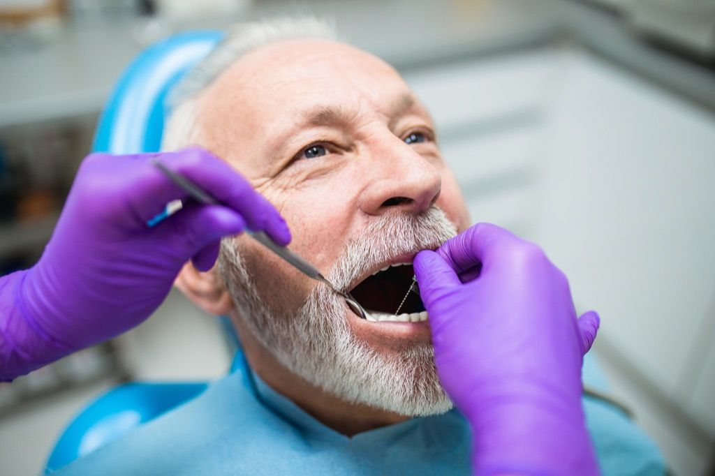 Home gran al dentista que es comprova les genives, preguntes de salut després dels 40 anys