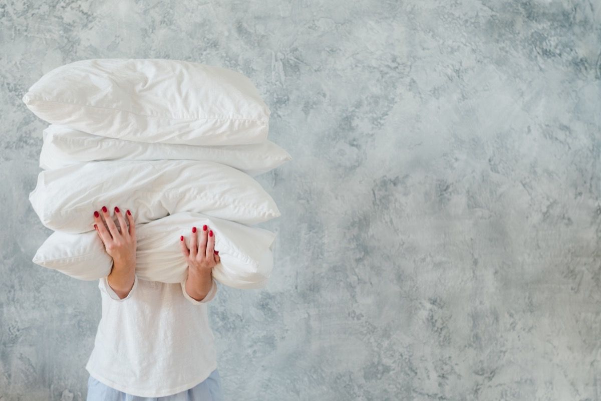 kvinne holde haug hvite puter sengetøy sove