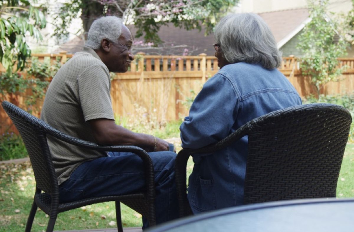 starší černý pár mluví venku na zahradě