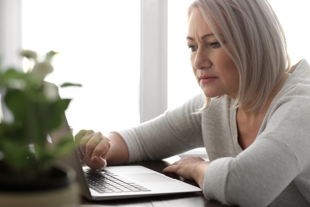 femeie senior care se uită fix la laptop
