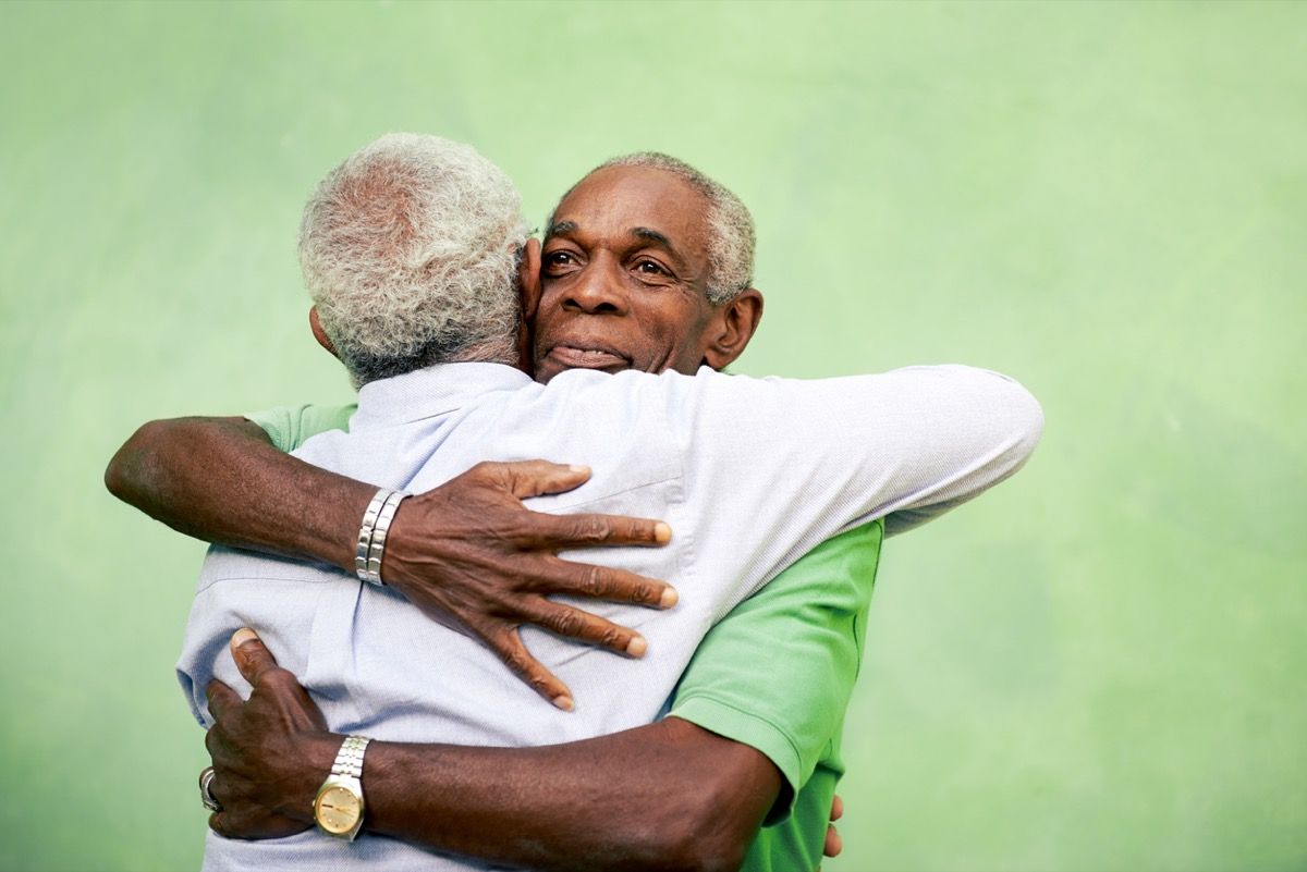 Dva starejša temnopolta moška, ​​ki se objemata na prostem