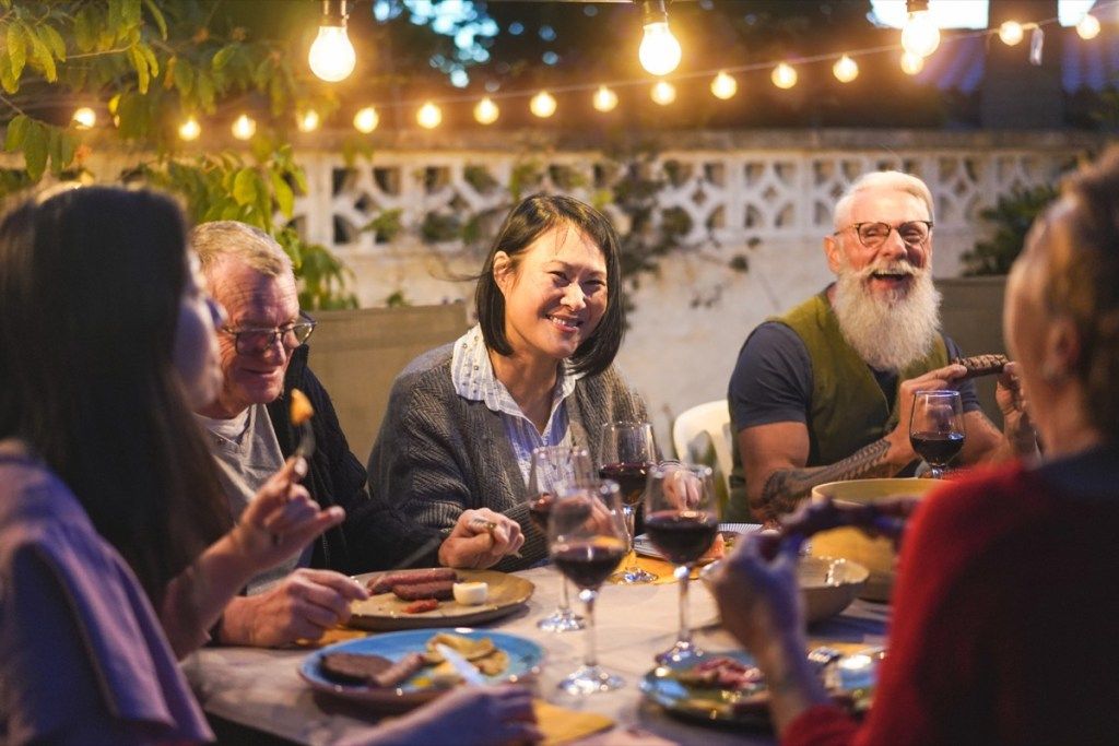 gruppo di amici e famiglia che cenano a un tavolo, domande sulla salute dopo i 40 anni