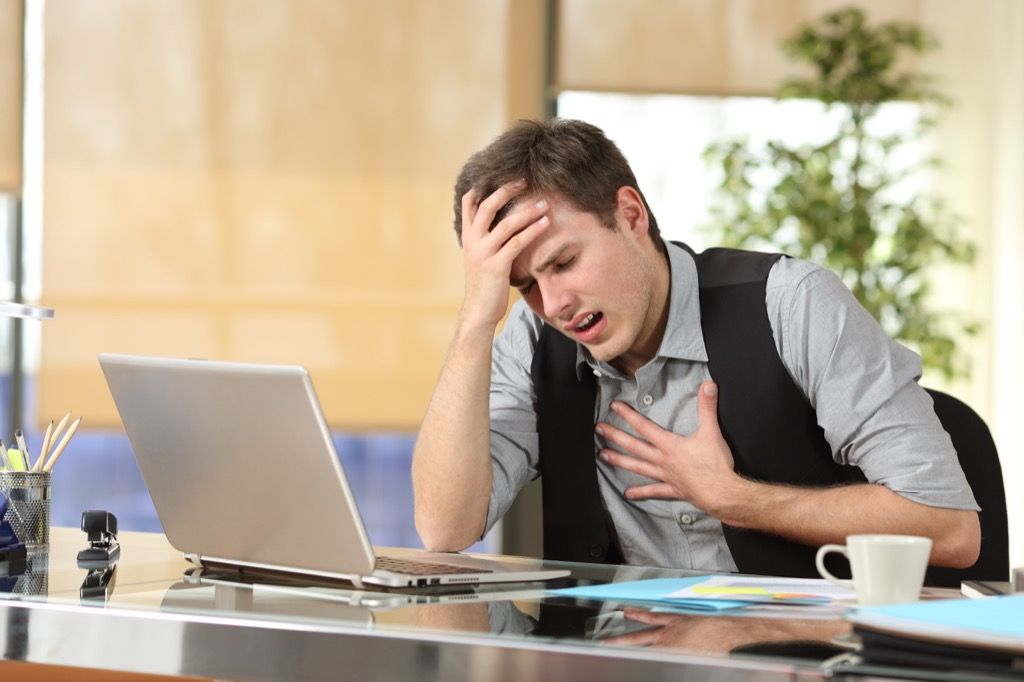 Hombre que sufre de un ataque de pánico en el trabajo bajo estrés