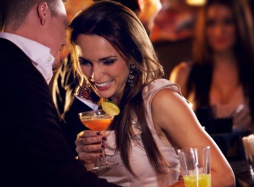 женщина смеется с напитком в руке