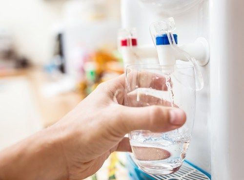Llenado de vaso con agua en primer plano del enfriador de agua
