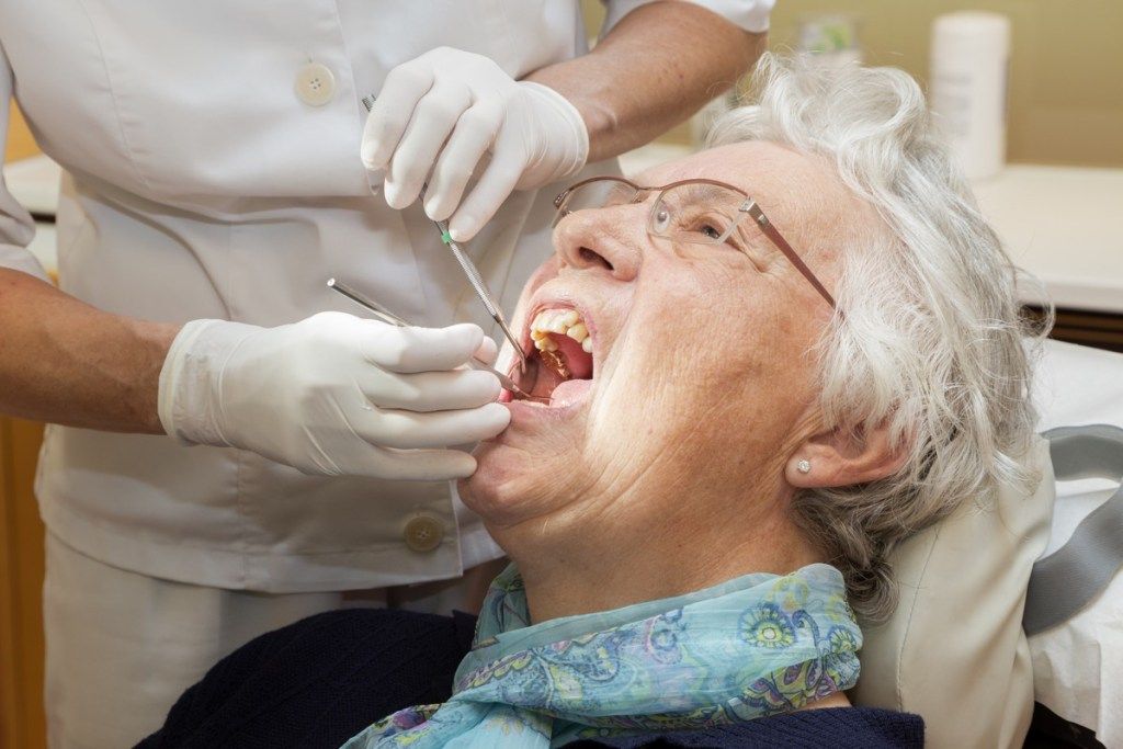En eldre kvinne som får munnen sjekket ut hos tannlegen, subtile symptomer på alvorlig sykdom