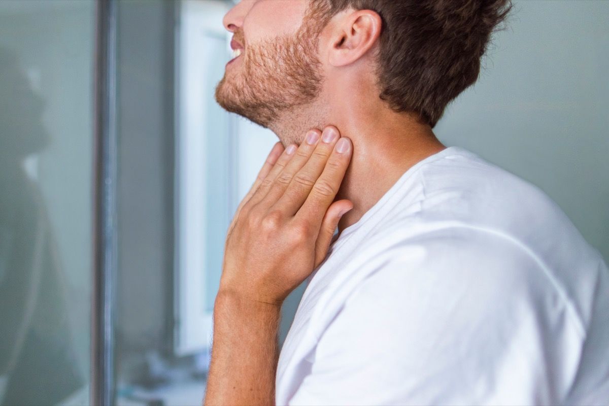 Човек проверява подутата щитовидна жлеза