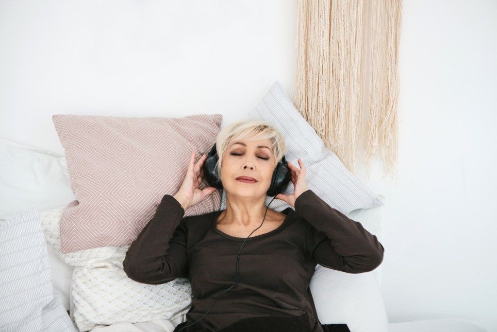 Positiv eldre kvinne som hører på musikk. Den eldre generasjonen og nye teknologier