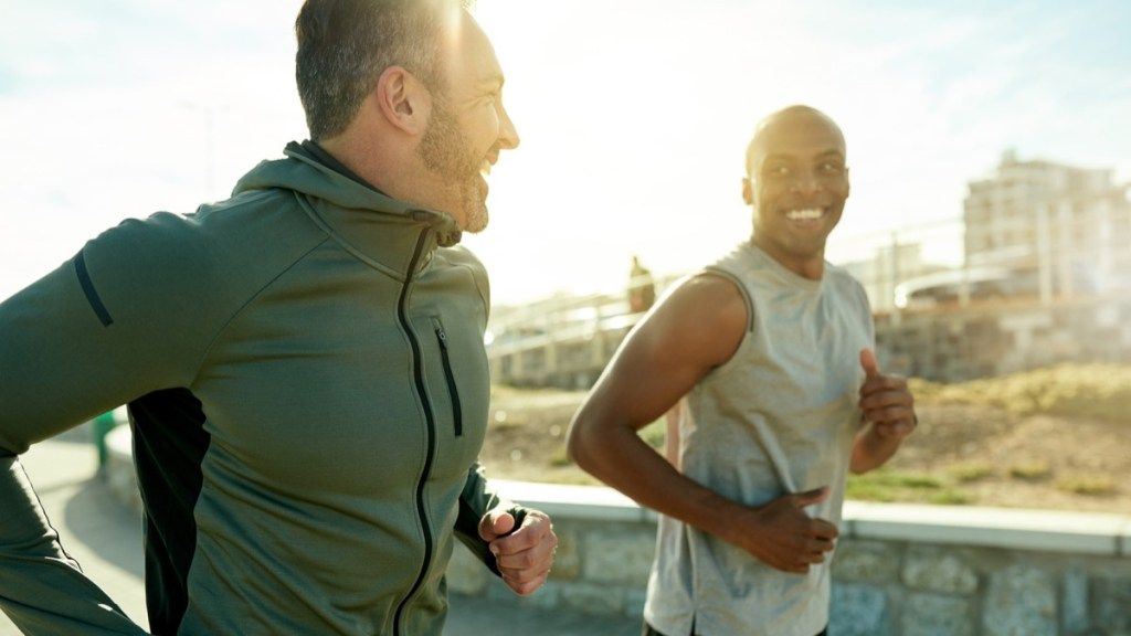 सफेद आदमी और काले आदमी बाहर दौड़ रहे हैं और एक-दूसरे को देखकर मुस्कुरा रहे हैं