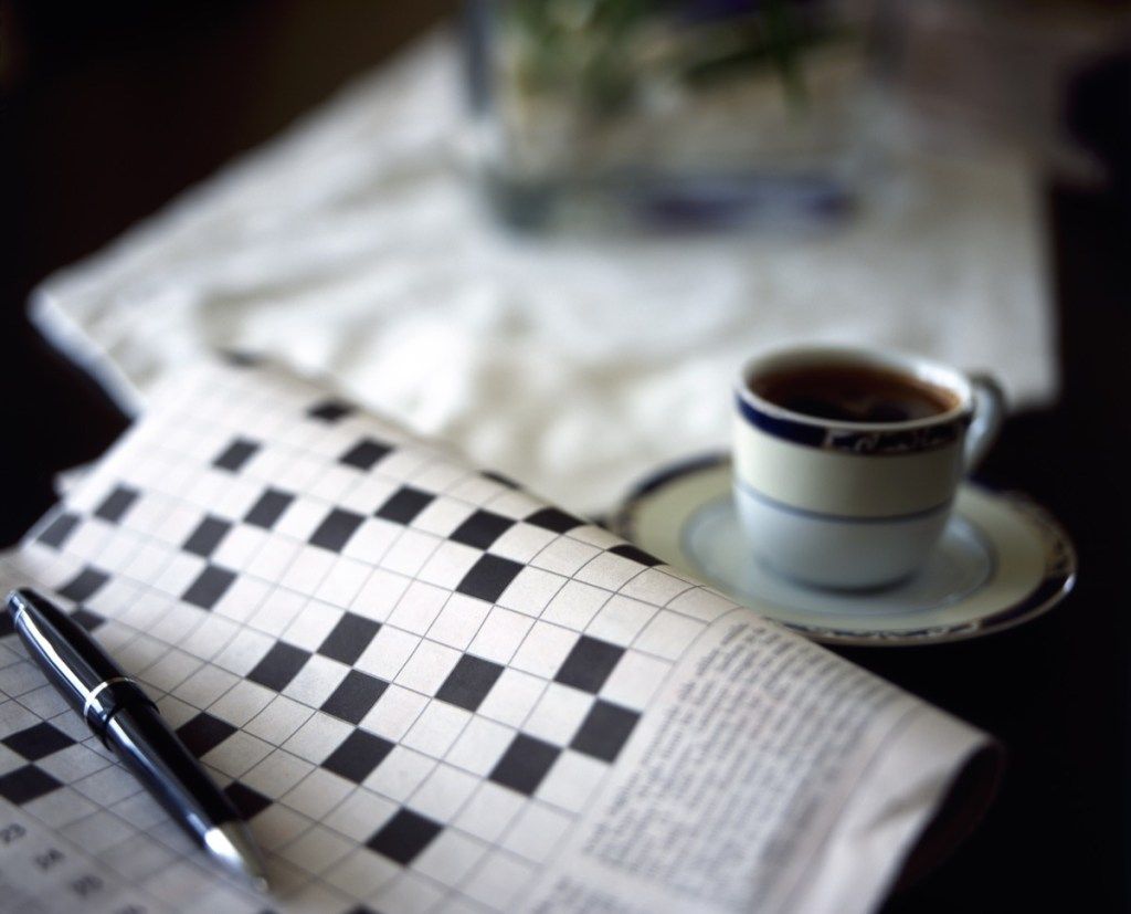 leeres Kreuzworträtsel mit einem Stift und schwarzem Kaffee