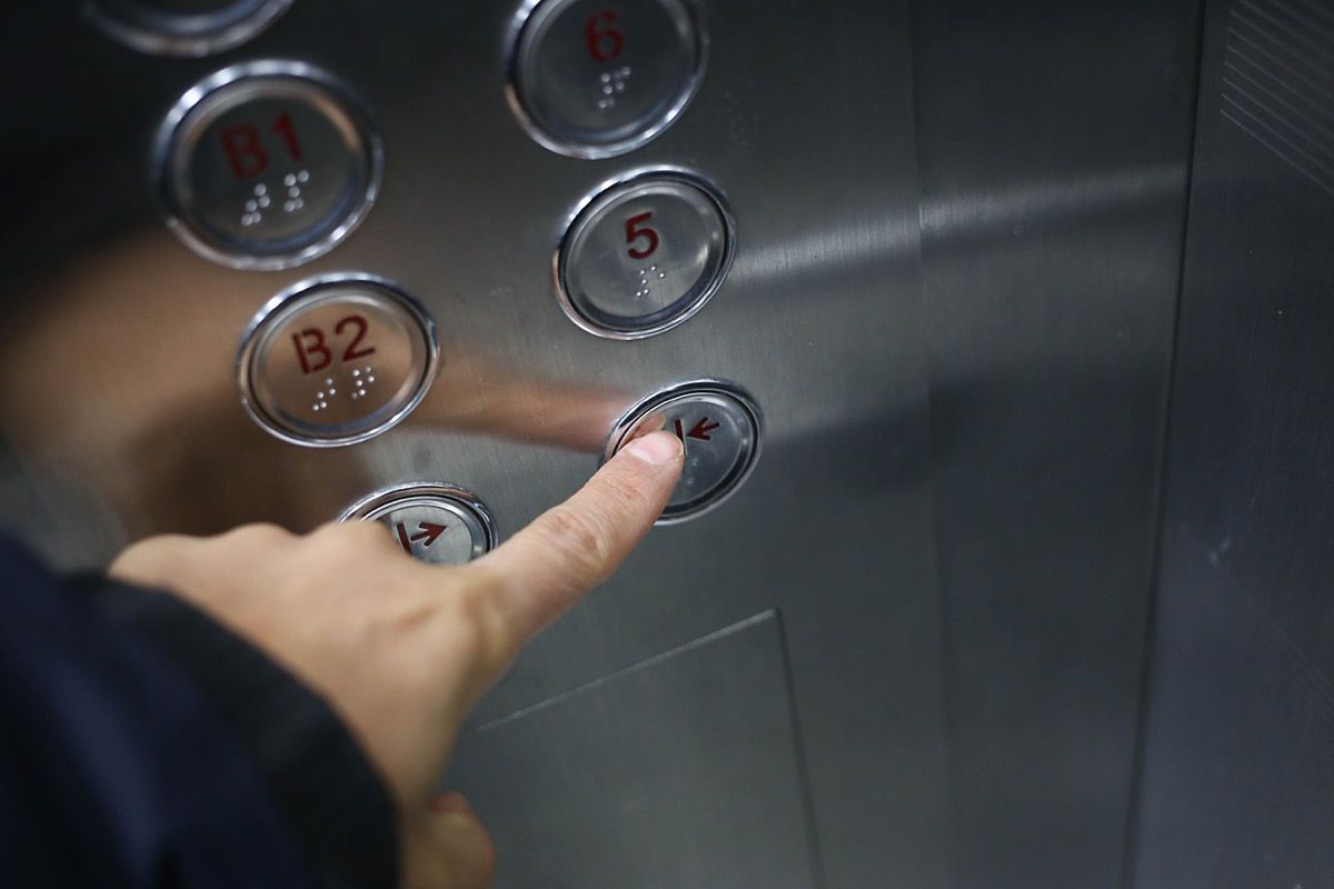 エレベーターのドアを閉めるボタンを押す男
