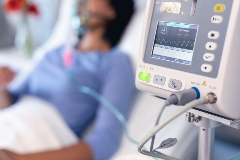   Monitor de ventilador y paciente en cama de hospital con ventilador de oxígeno.