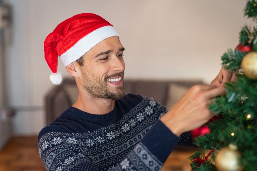 Mann som pynter et juletre med ornamenter
