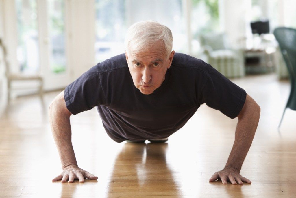 Eldre mann gjør push-ups hjemme