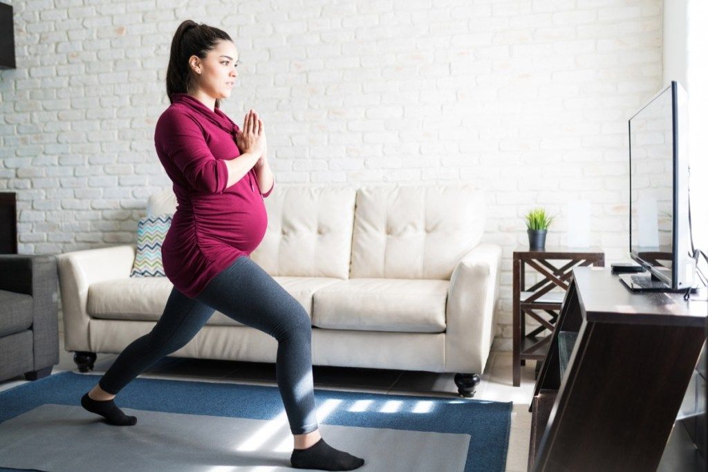 Zwangere vrouw doet lunges in haar woonkamer