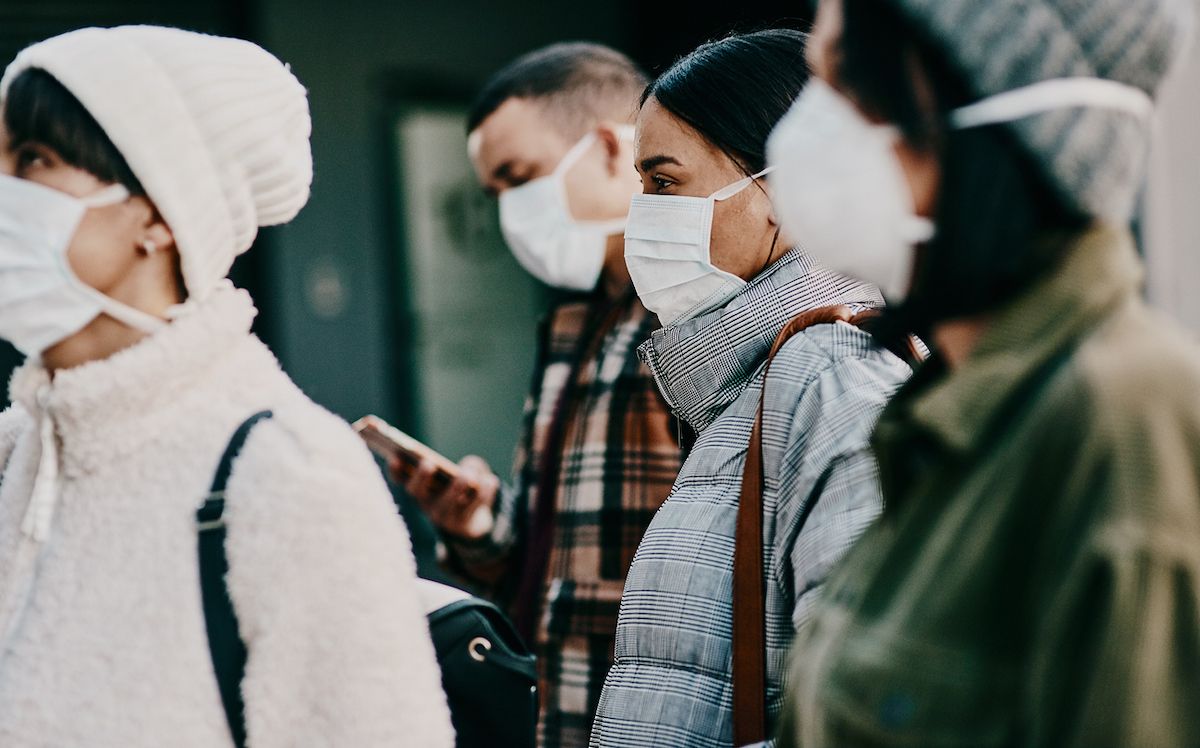 ठंड के मौसम में सड़क पर मास्क पहने युवाओं के एक समूह का शॉट