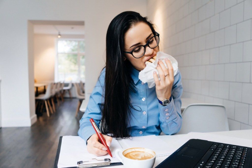 kvinna som äter medan du arbetar, etikett på kontoret