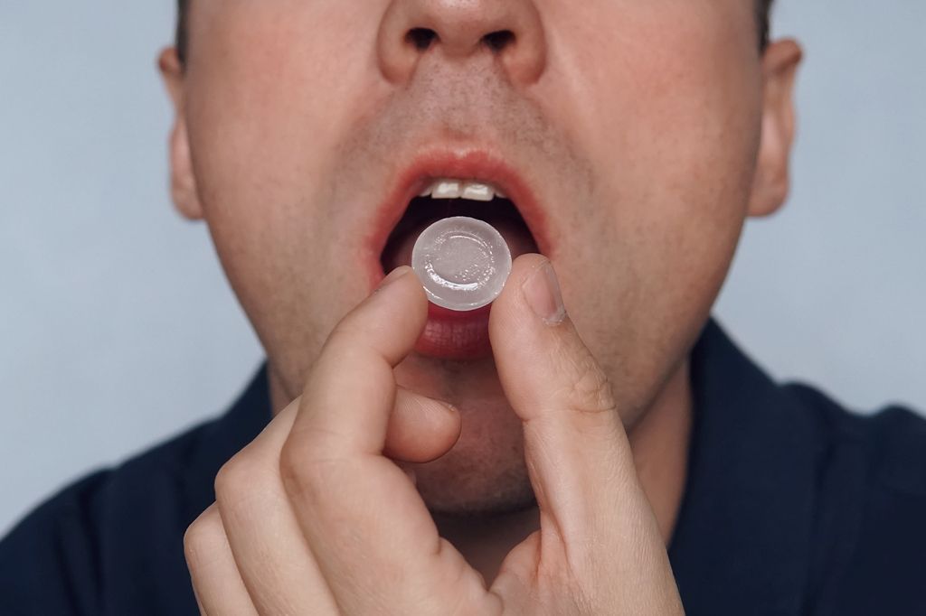 Homem chupando pastilha para tosse, faz mal para os dentes