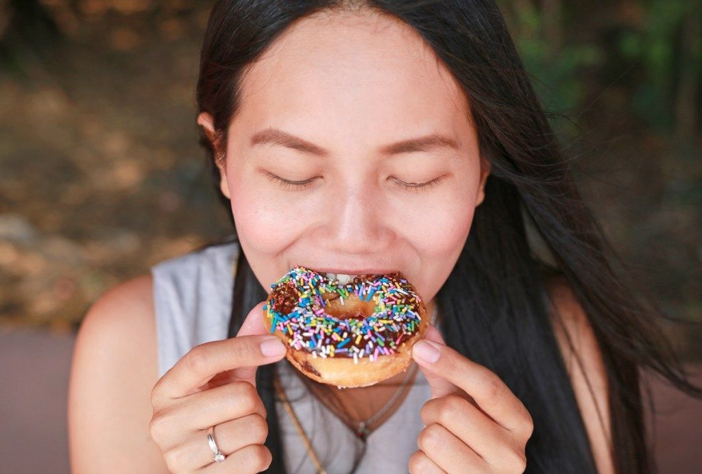 joven mujer asiática comiendo donut espolvoreado