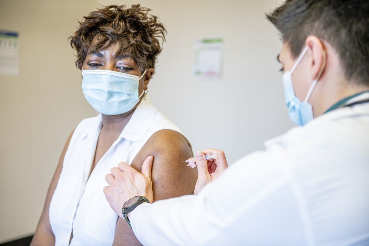 หญิงสูงวัยกำลังได้รับการฉีดวัคซีนป้องกันไวรัสโควิด -19 จากแพทย์ชาย