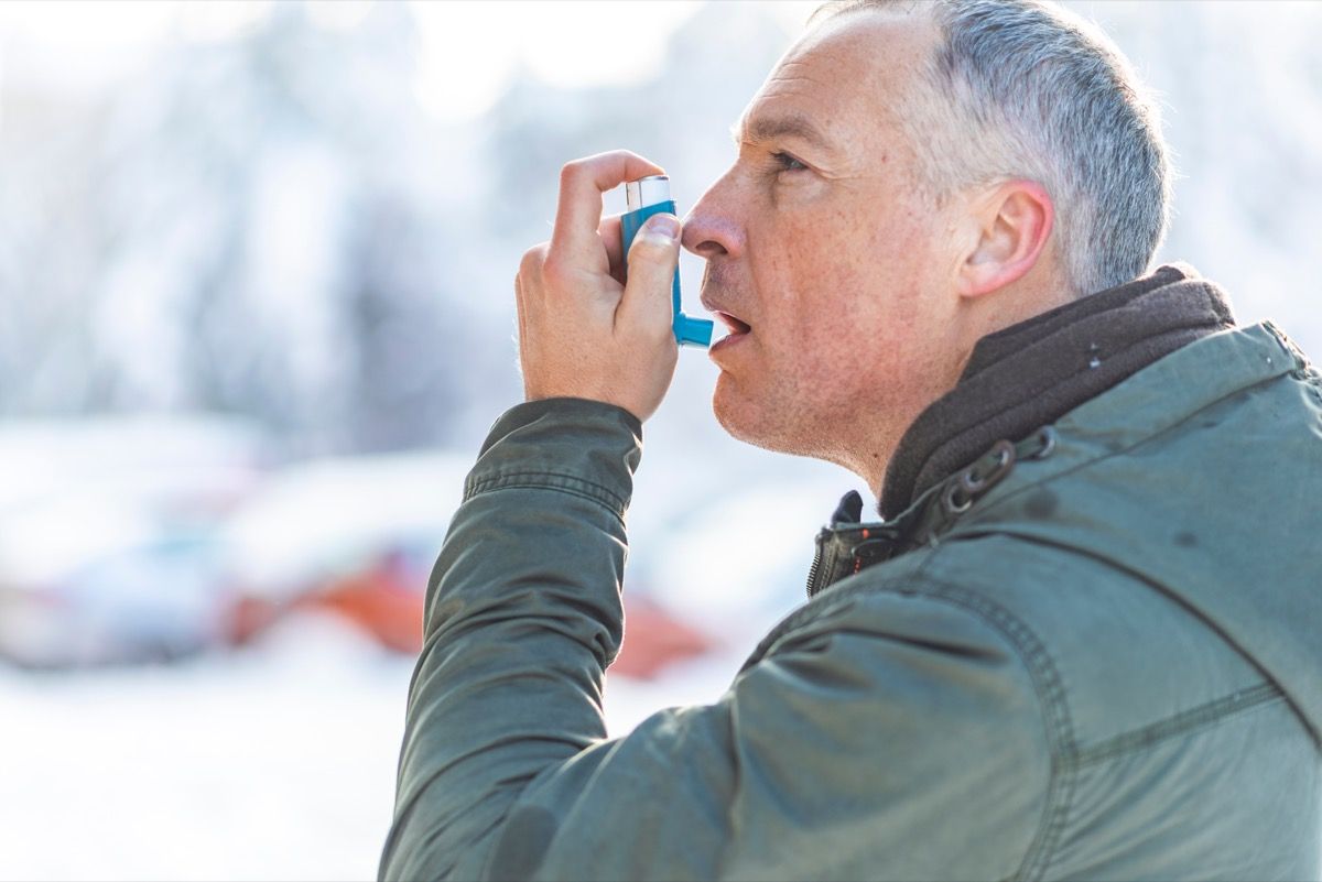 Hombre que usa un inhalador para sus factores de riesgo cardíaco de asma