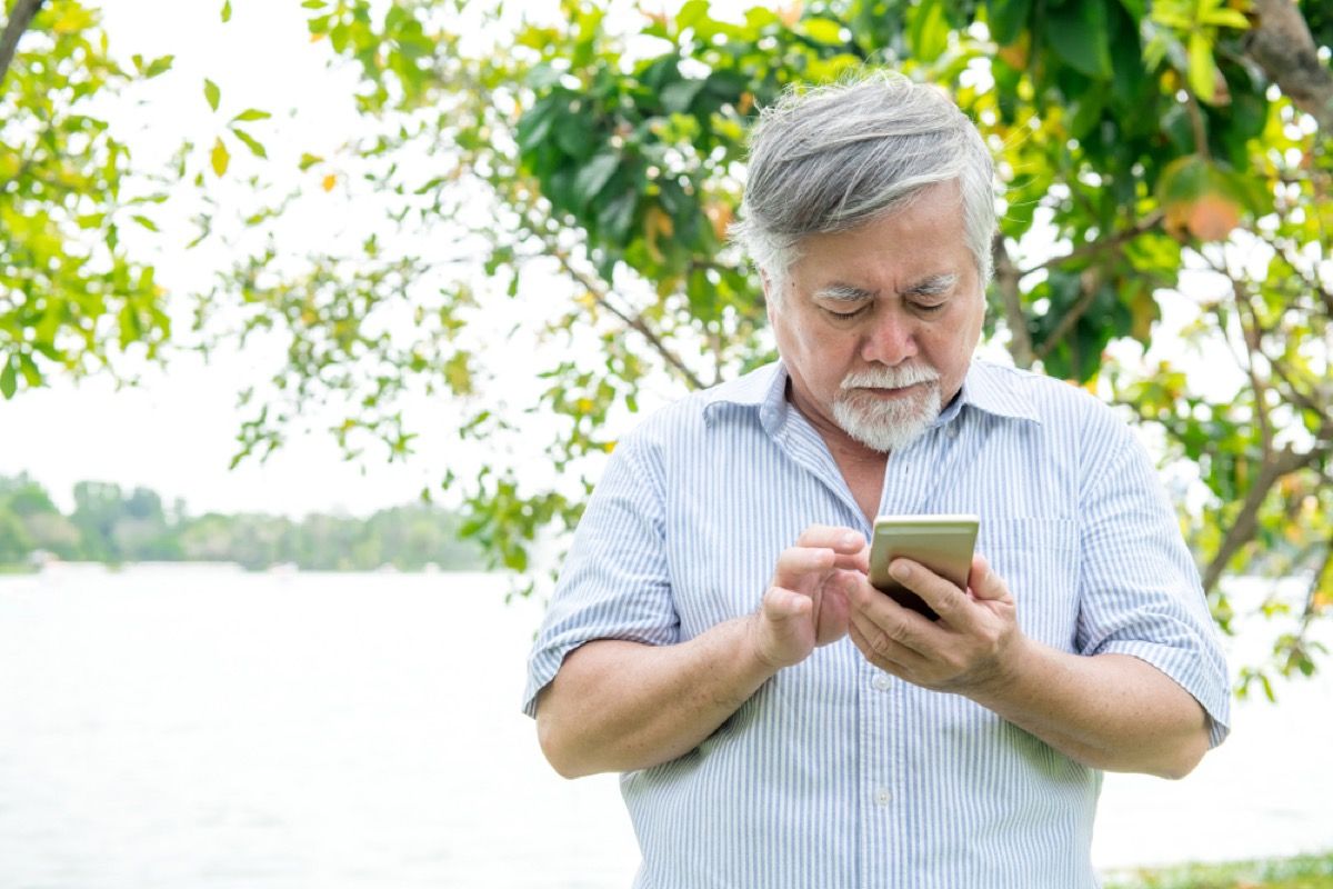senior Aziatische man verward door mobiele telefoon