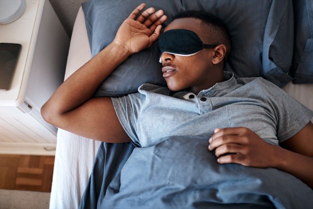 Obrezan posnetek čednega mladeniča v nočni maski in doma v svoji postelji
