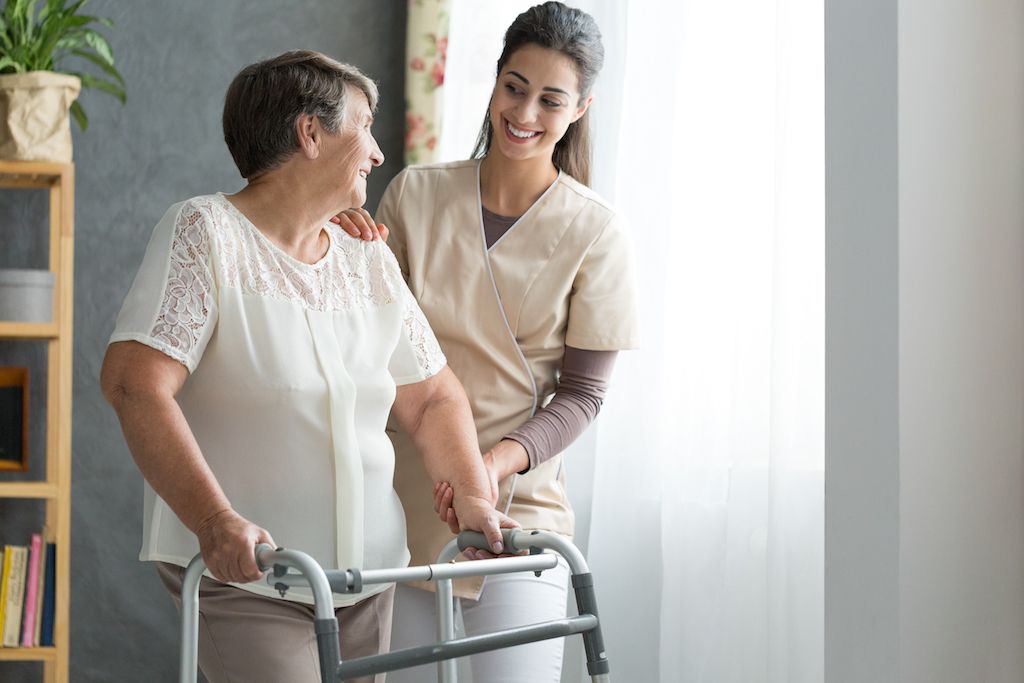 stará žena pomocou chodítka, keď sa zotavuje z operácie bedrového kĺbu