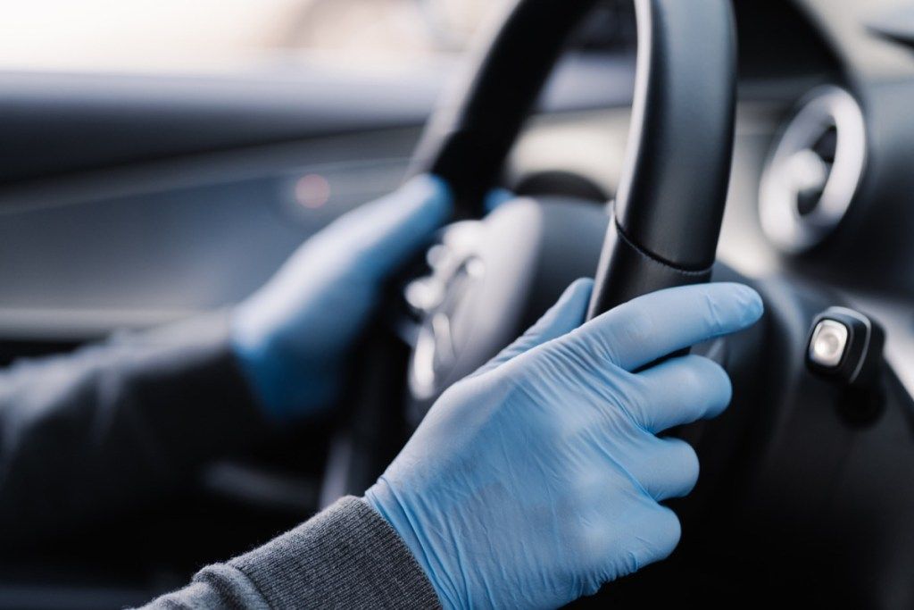 ręce w niebieskich rękawiczkach trzymając kierownicę