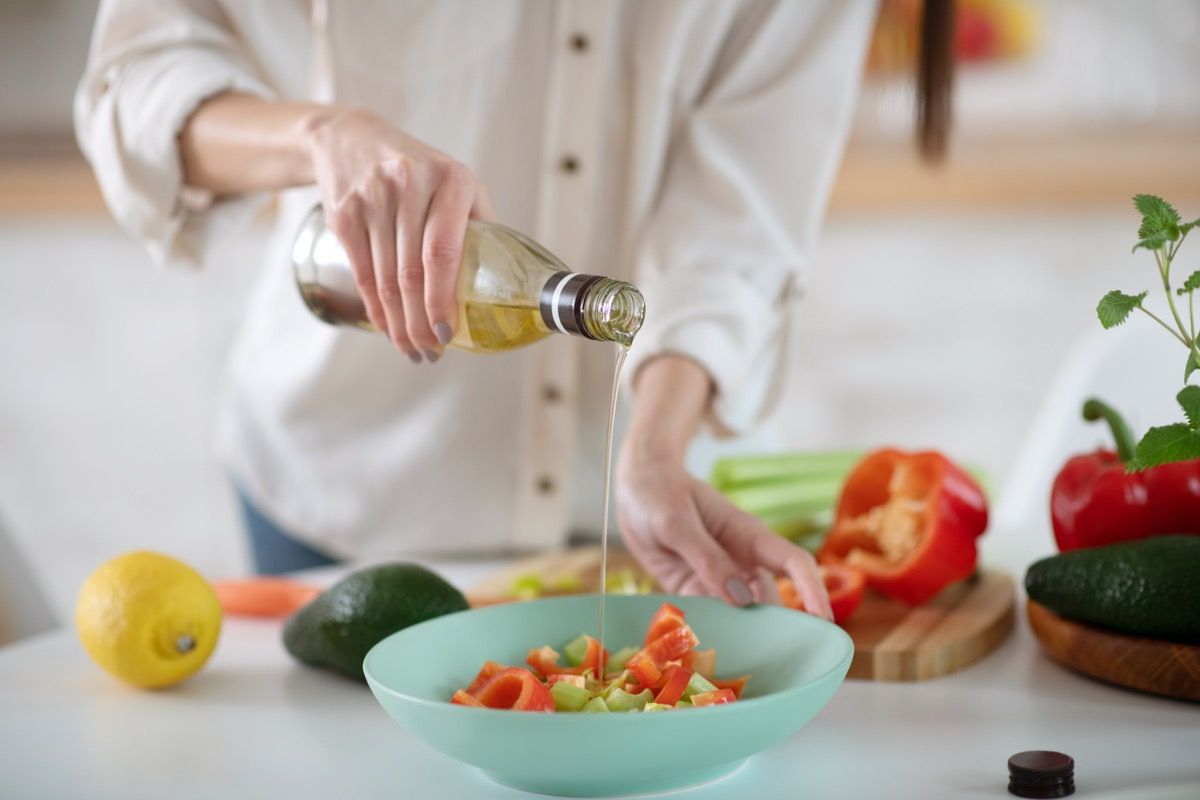 Žena koja poliva maslinovim uljem salatu s avokadom