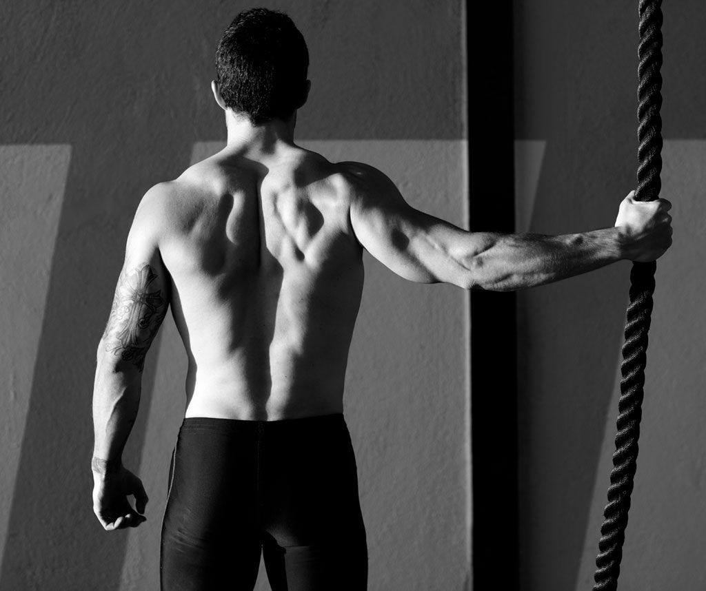 Hombre musculoso en el gimnasio sosteniendo una cuerda six-pack abs
