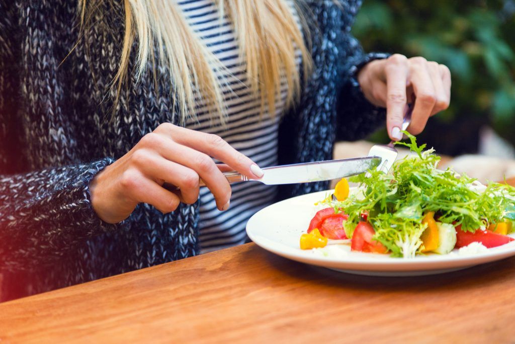 Sieviete ēd bēdīgus salātus ar sešiem iepakojumiem