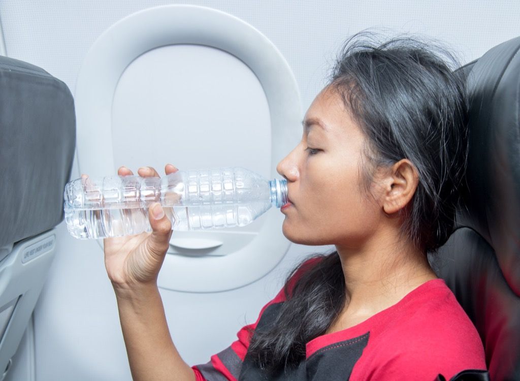 Người phụ nữ uống nước trên máy bay.