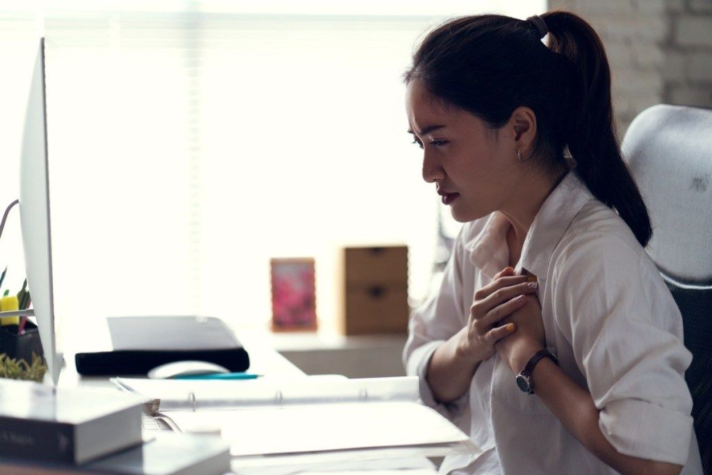 bir ofiste göğsünü tutan bir kadın, soğuk algınlığının ciddi olduğunu belirtiyor