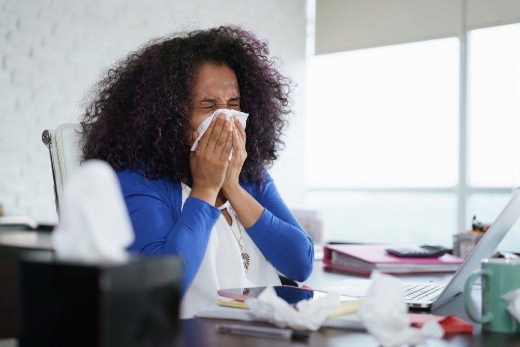 kvinna nyser i vävnad, tecken på att din förkylning är allvarlig