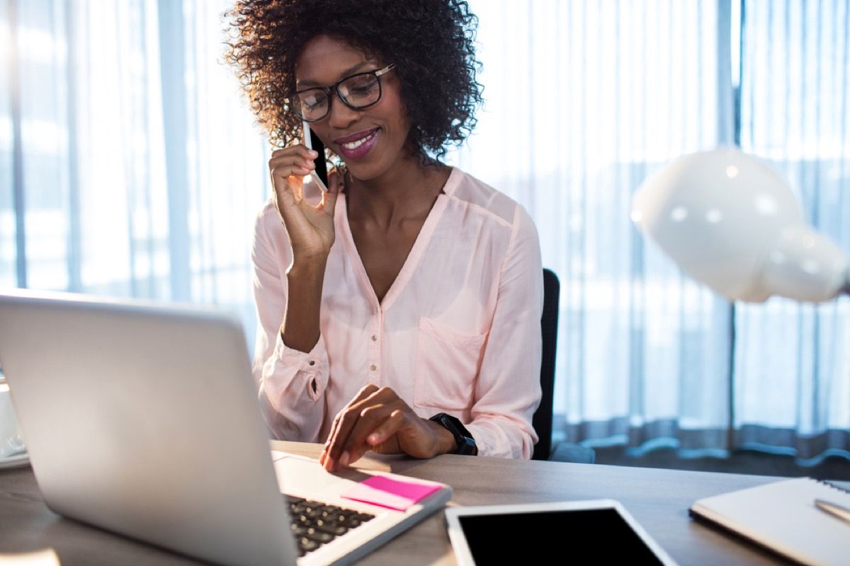 musta nainen puhuu puhelimessa toimistossaan kannettavan tietokoneen edessä, ei puhua asiakaspalvelun edustajalle