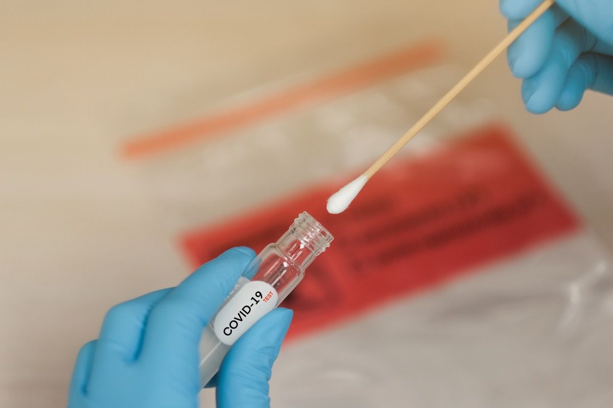 ръце в ръкавица в лаборатория, поставяне на тампон във флакона за тест за коронавирус