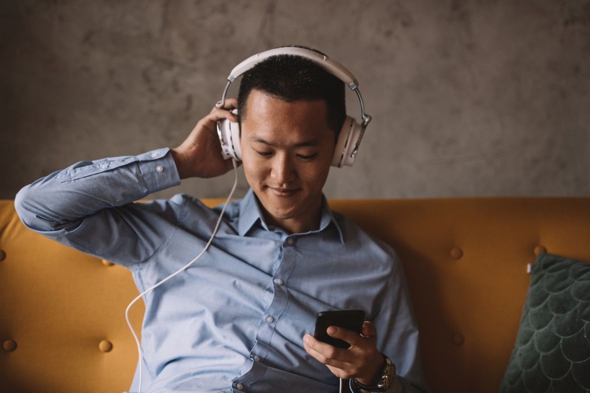 ชายหนุ่มชาวเอเชียกำลังฟังเพลงและผ่อนคลายในห้องทำงาน