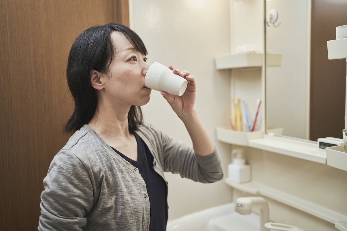 אישה מגרגרת עם שטיפה דרך הפה בחדר הרחצה