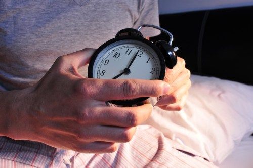 Person, die Uhr vor dem Schlafengehen für Wecker einstellt