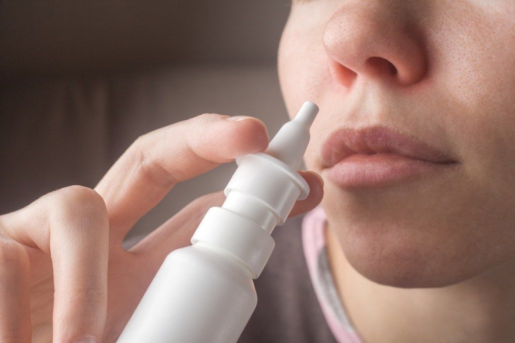 Kvinne som bruker nesespray for forkjølelse